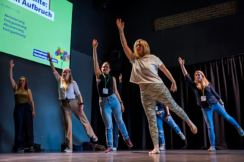 Bewegungspause auf der Bühne: Mehrere Frauen machen Dehn- und Balanceübungen unter dem Motto „Aktivierung – Entspannung“