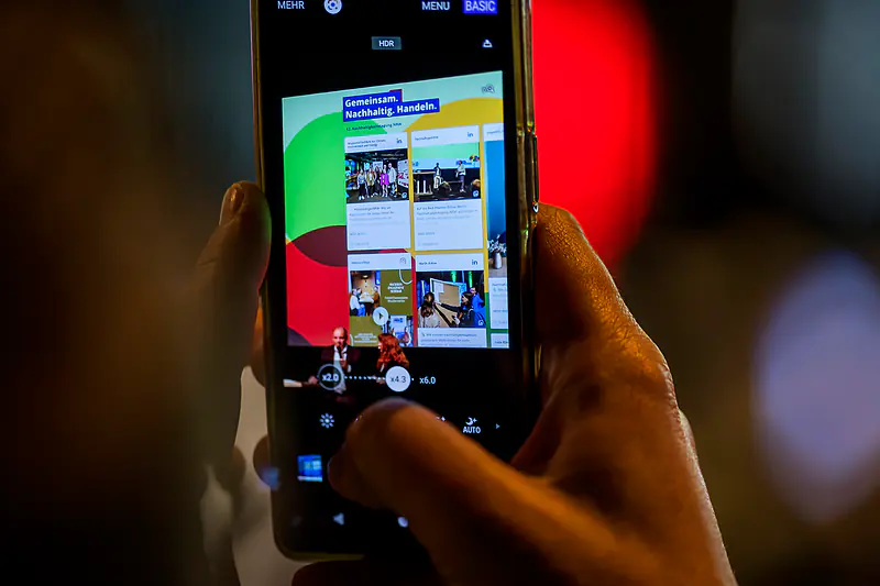 Ein Smartphone fotografiert die Social Wall der Tagung mit Beiträgen zum Tag