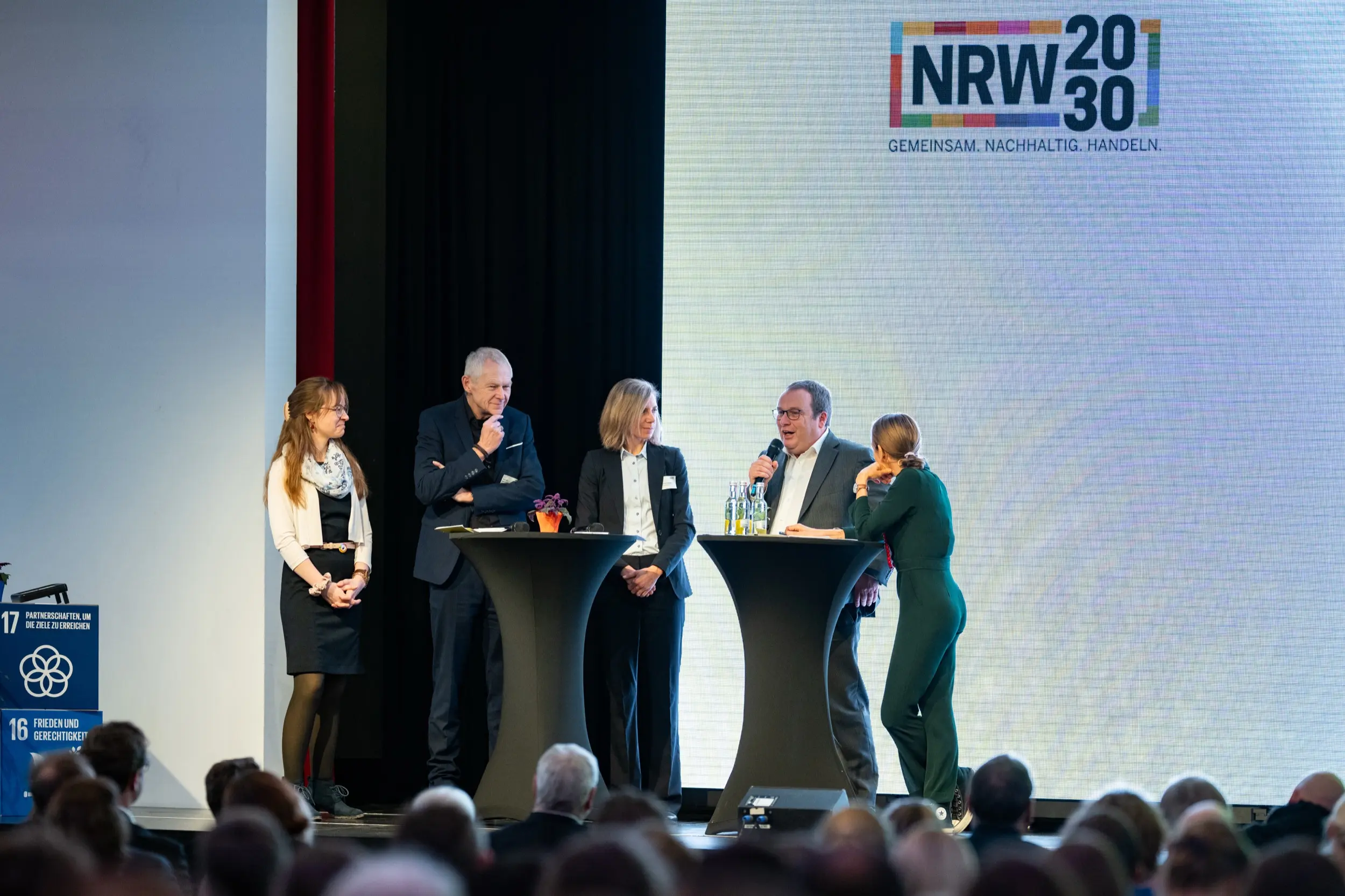 Dieses Foto zeigt Menschen aller Altersklassen, sitzen in einem Saal bei einer vergangenen Nachhaltigkeitstagung.NRW.